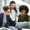 Three women discussing marketing data at a desk